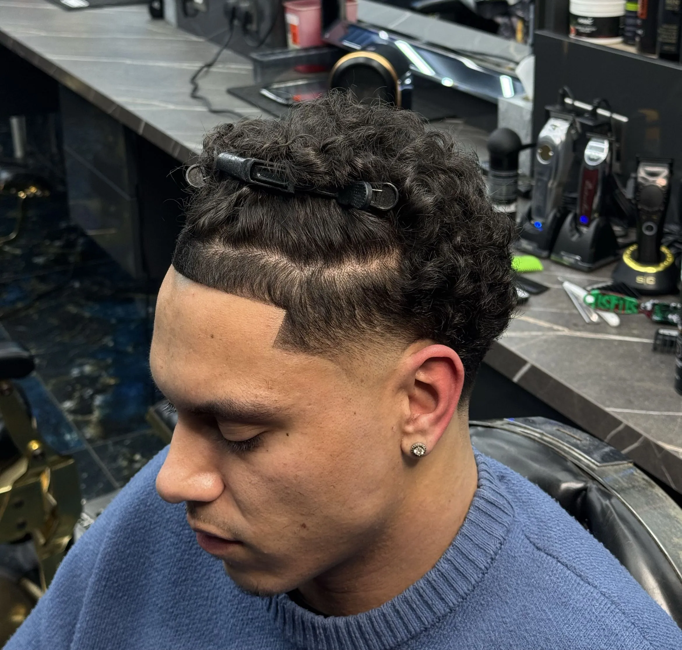 A curly top with a skin fade, cut at Millionhair