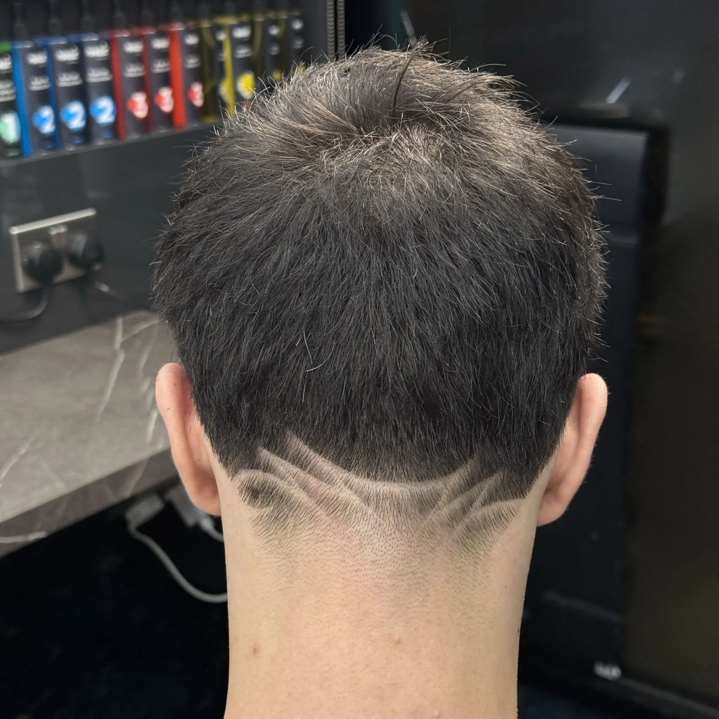 A freestyle design in a skin fade, against the shop’s black marble